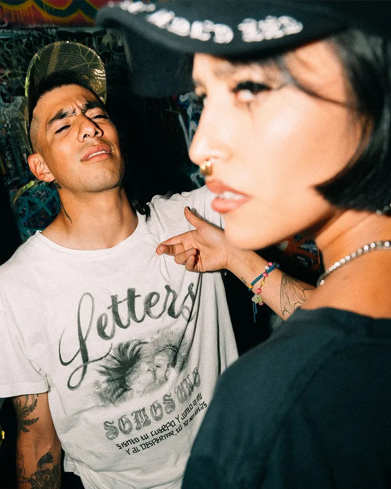 Two people in Somos Uno, one in the Letters tee, one in the Padre Black hat
