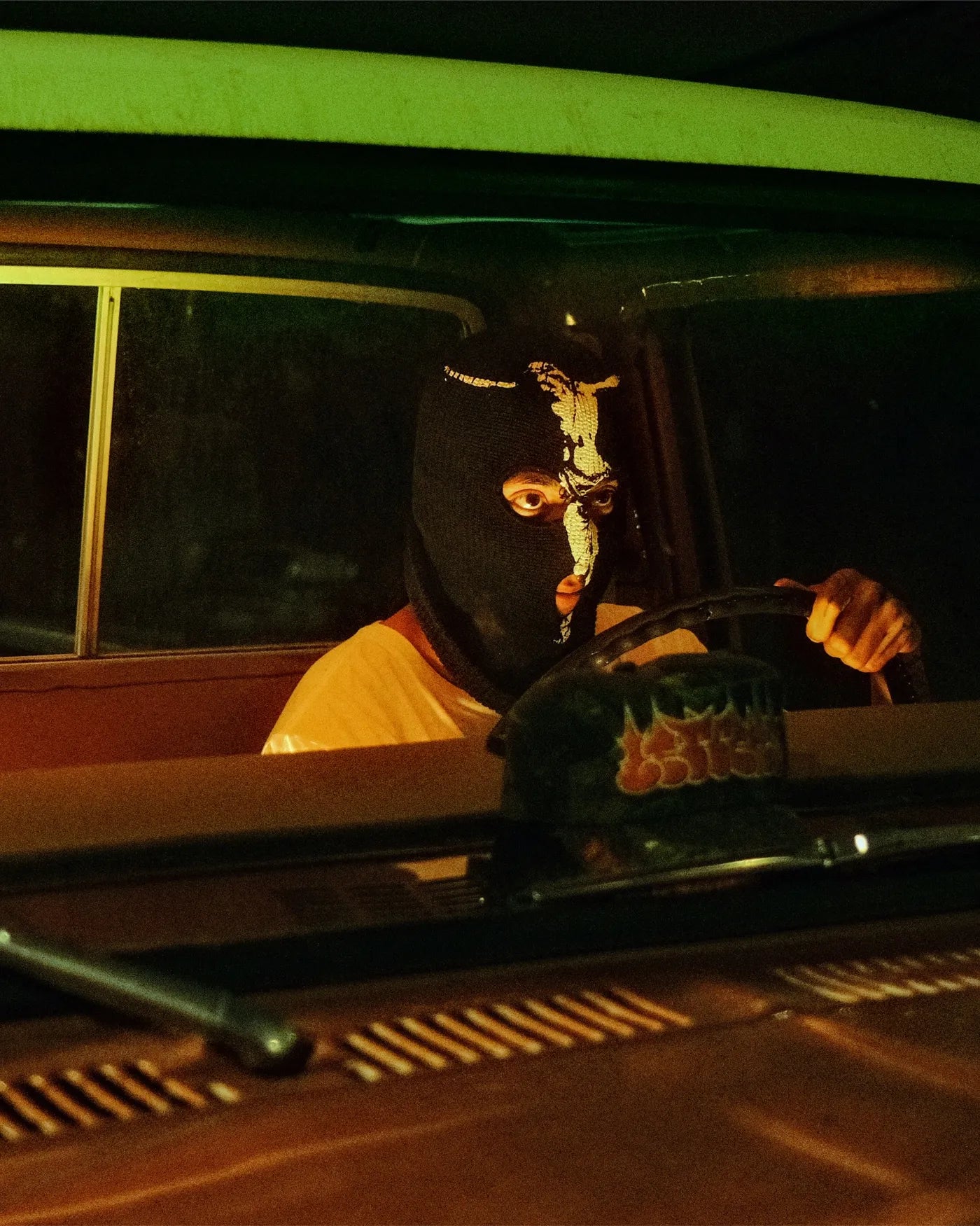 A masked figure in a pickup truck at night, from Letters